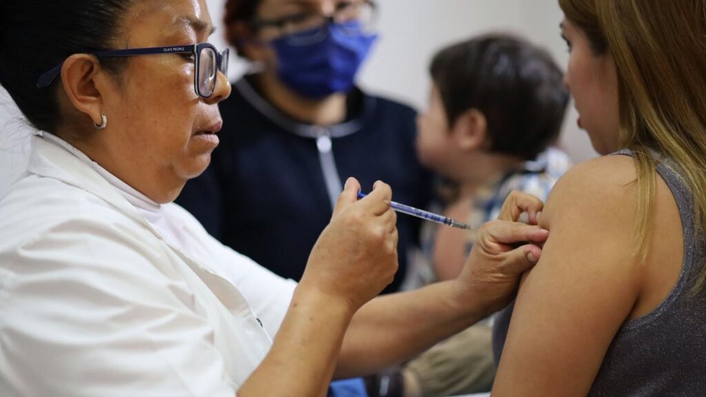 Aplicación de vacuna SRP en un centro de salud de Michoacán, con personal de enfermería revisando la Cartilla Nacional de Salud para completar esquemas de inmunización.