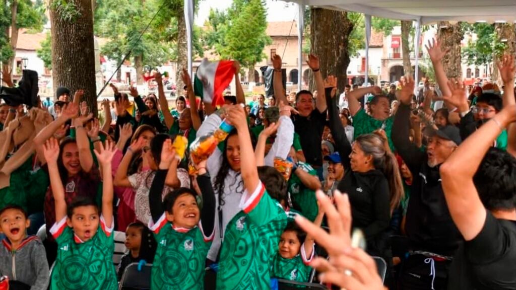 Familias y aficionados siguen el partido entre México y Sudáfrica durante el Jalo Futbolero en la Plaza Vasco de Quiroga de Pátzcuaro.
