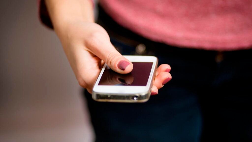 Usuario utiliza un teléfono celular mientras avanza el debate sobre el registro de líneas móviles.